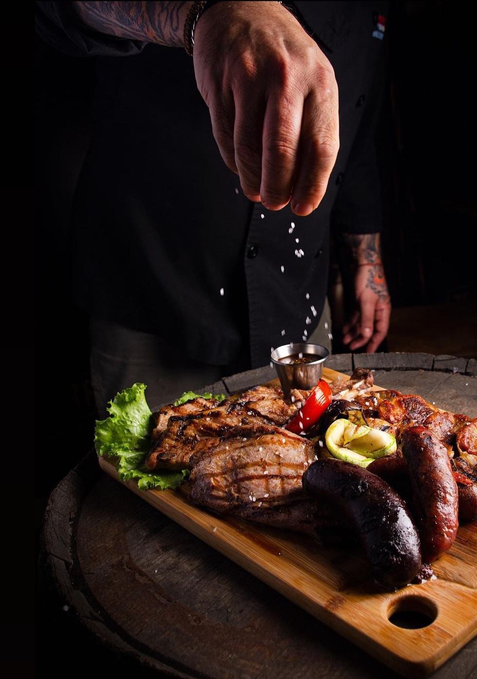 Mano del cocinero salando la tabla de parrillada