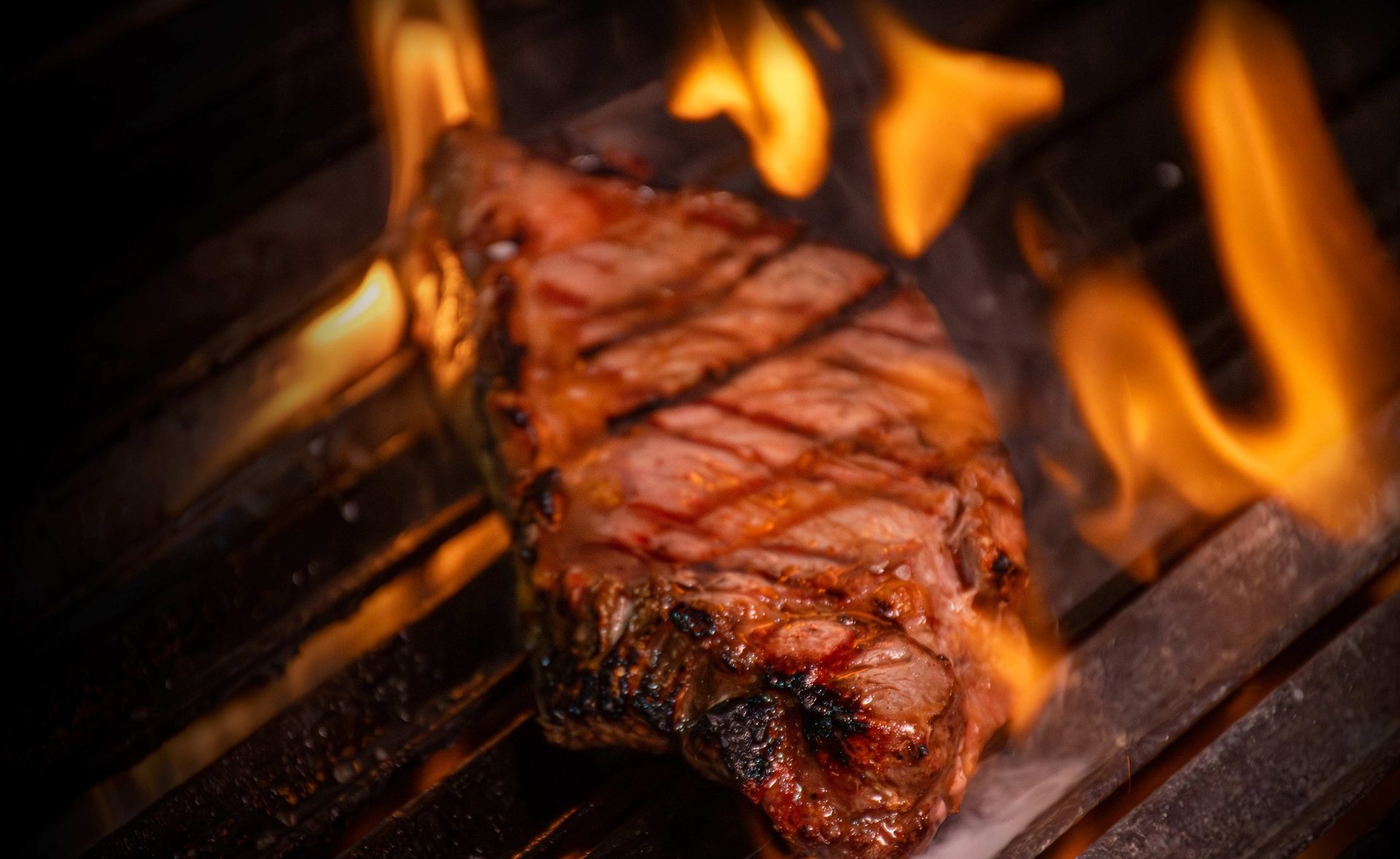 Corte de carne entre llamas sobre la parrilla