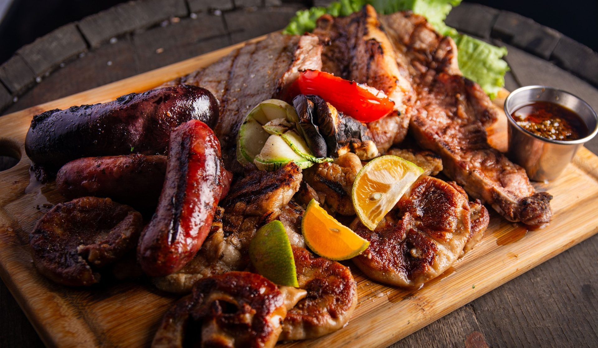 Tabla de parrillada argentina con cortes, chorizo y morcilla sobre un barril